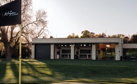 the rear elevation of the golf studio at the grove pictured at dusk with the taylormade flag visible in the foreground