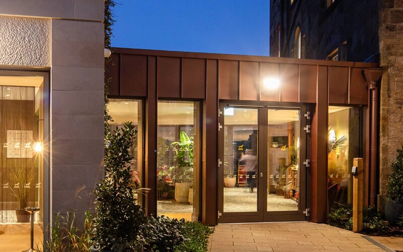 Glazed Link in Northumberland with aluminium double doors, shown at dusk - Bailiffgate Hotel - IQ Projects